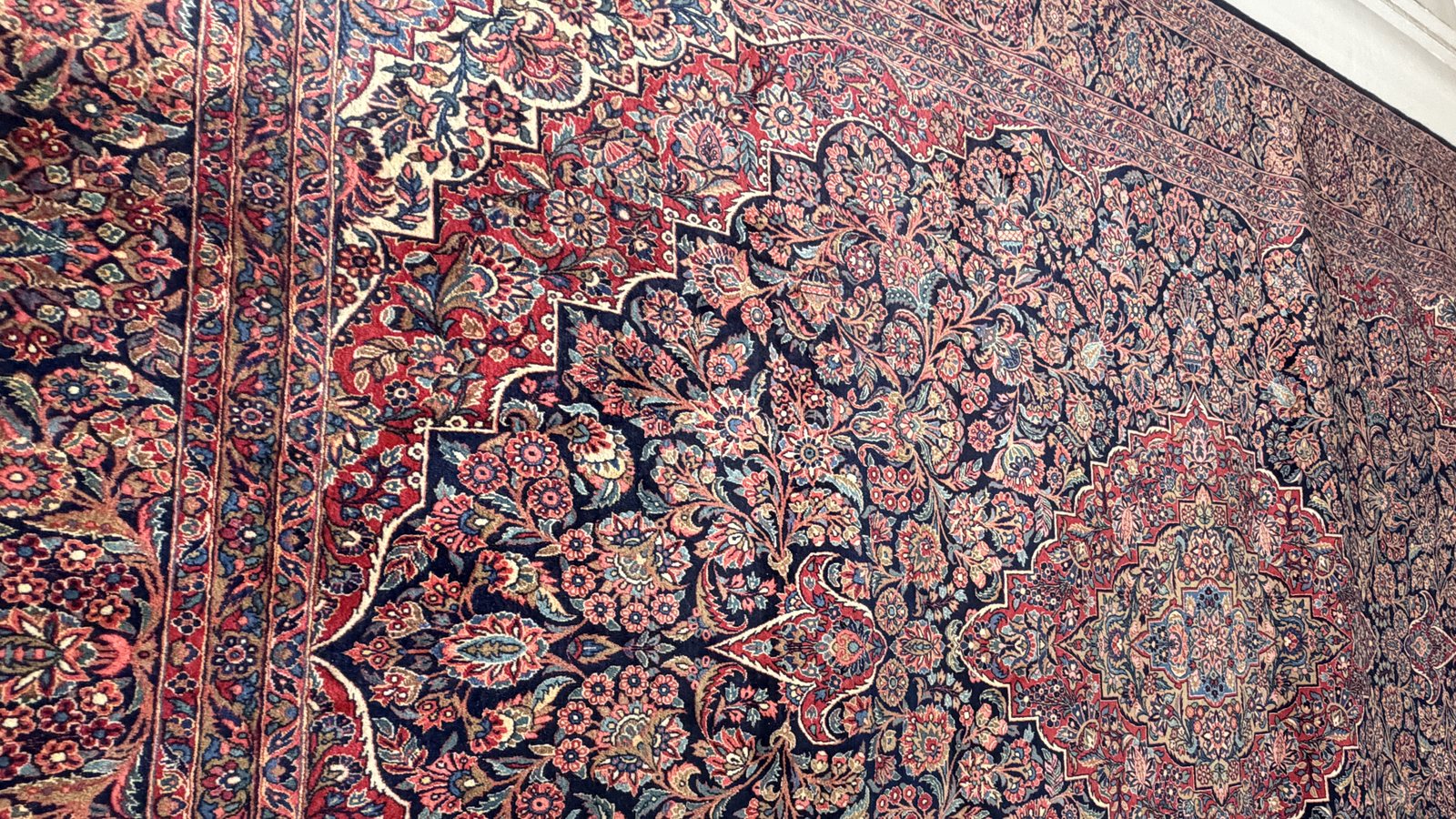 A washed hand-knotted rug laid out flat, rolled and ready to go back out for delivery