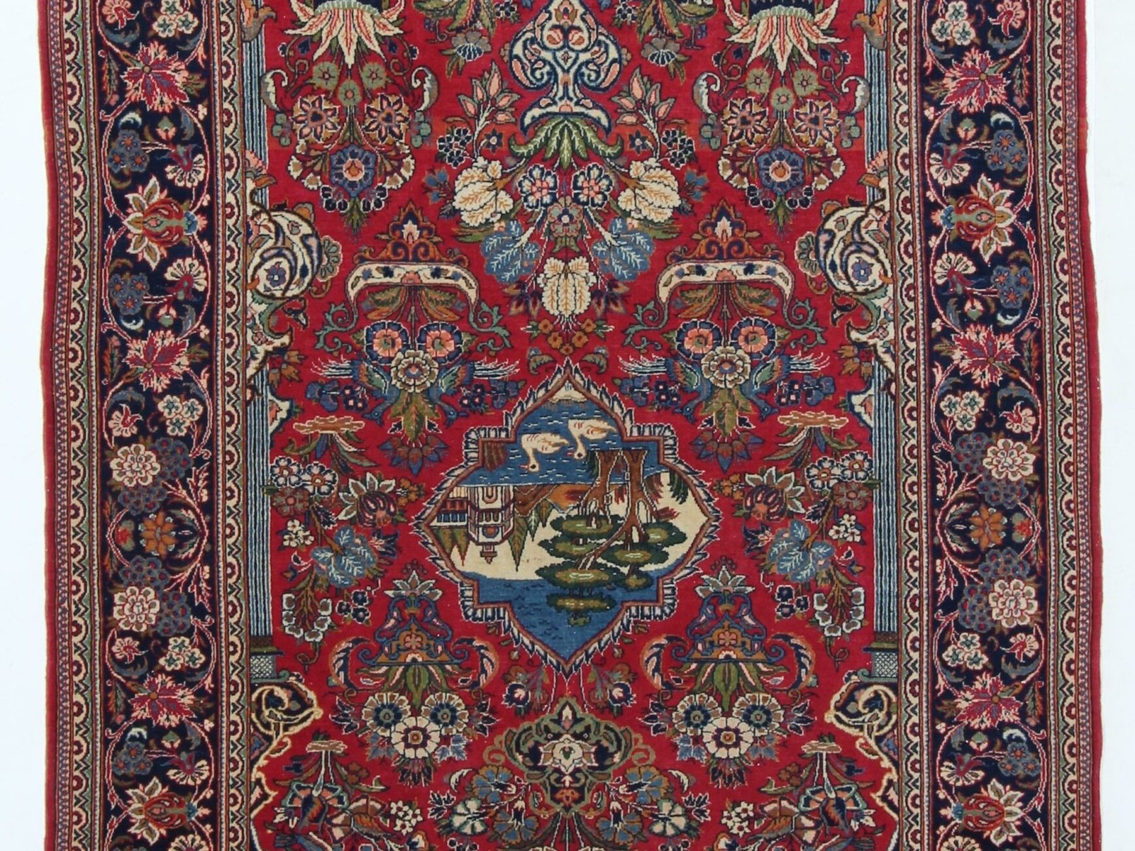 Detail of a hand-knotted Persian rug showing a curvilinear medallion in madder red and indigo